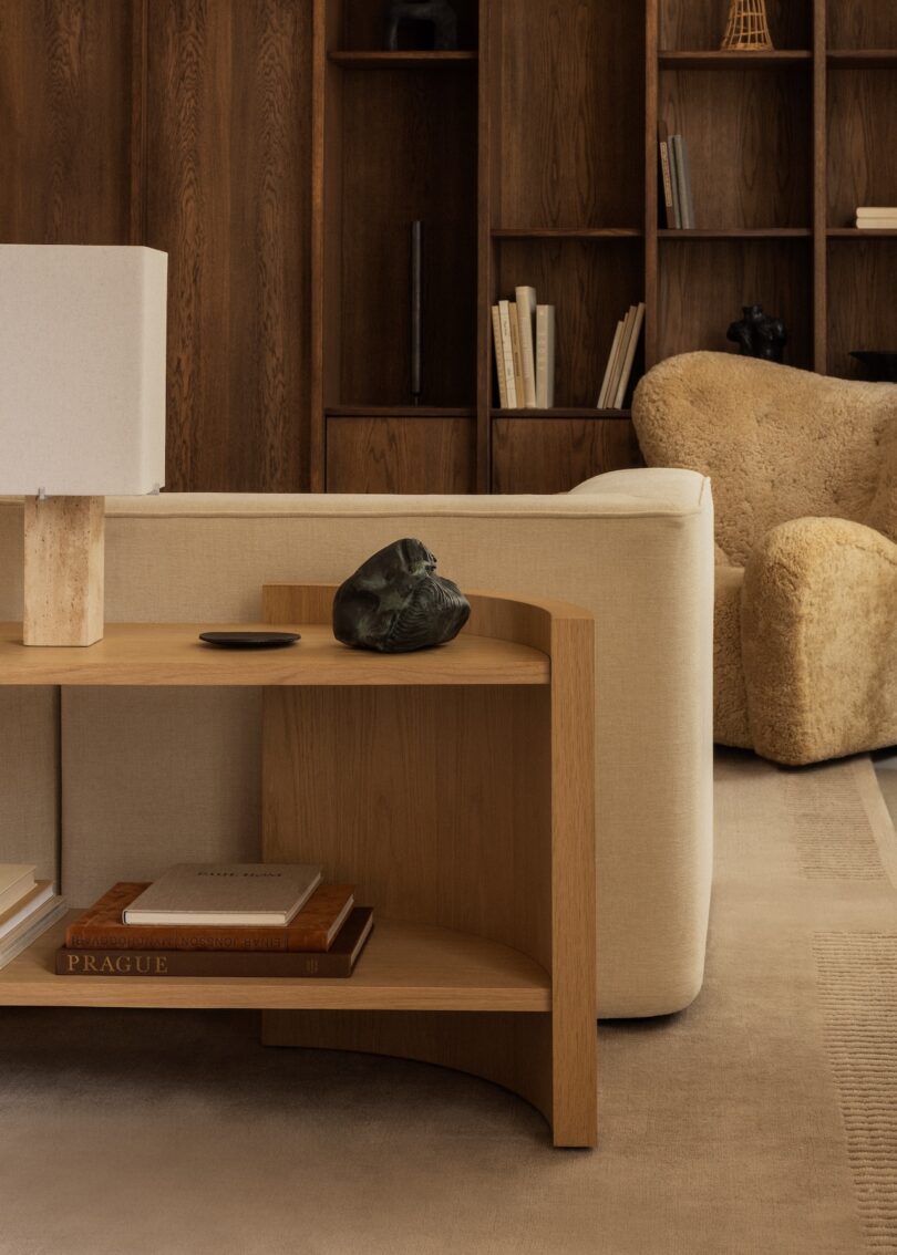 A modern living room featuring the Crescent shelving, a sculptural side table, and a cream sofa.