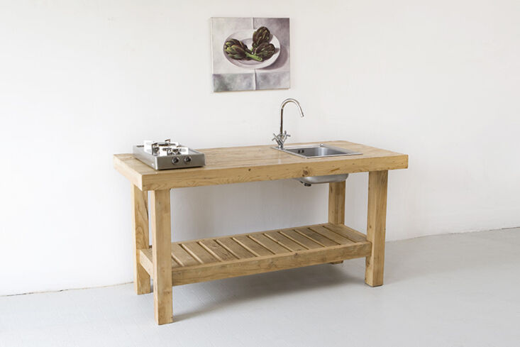 A rustic wooden kitchen island by Katrin Arens with a small integrated metal sink.