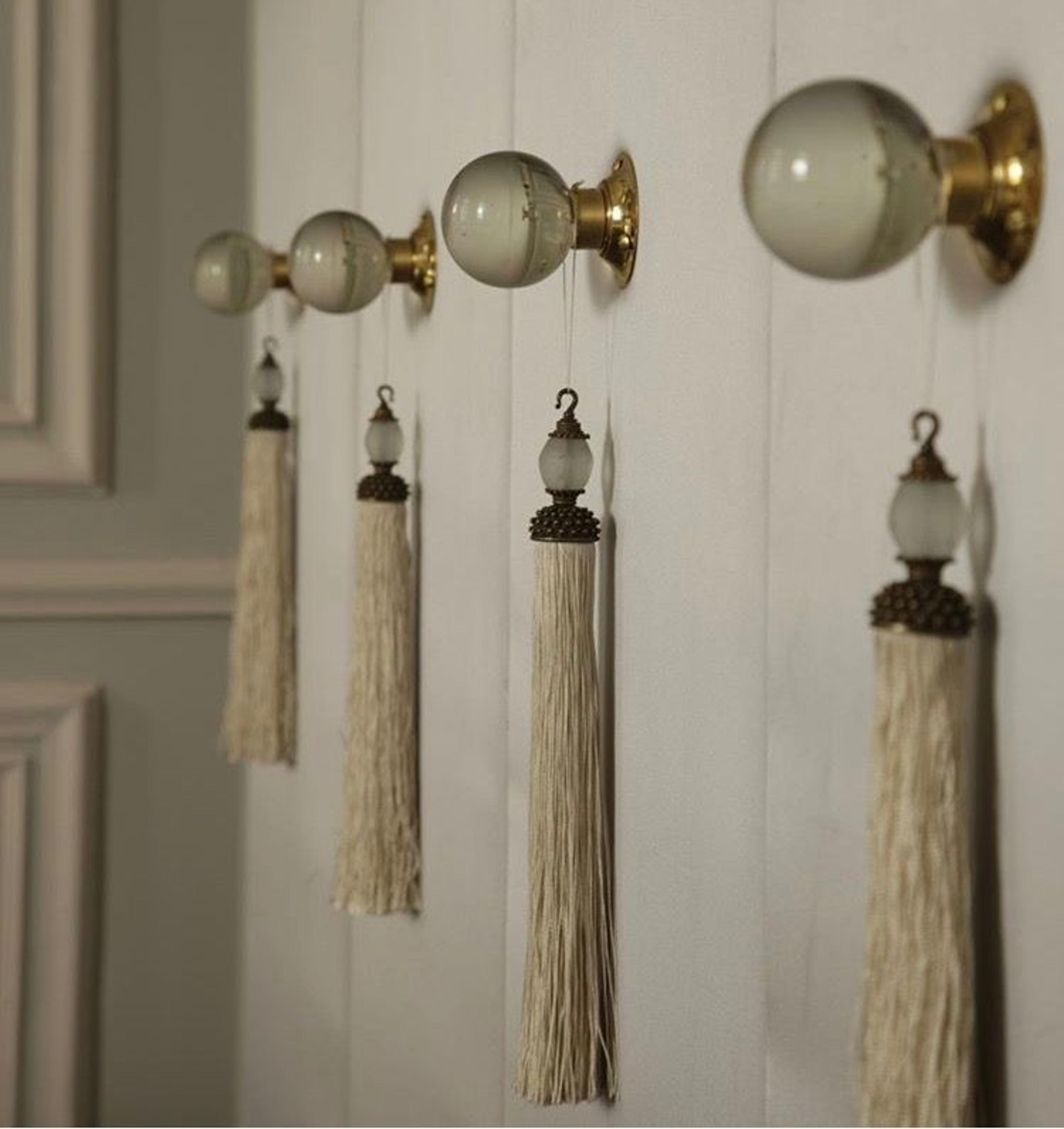 Decorative tassels hanging from a furniture knob.