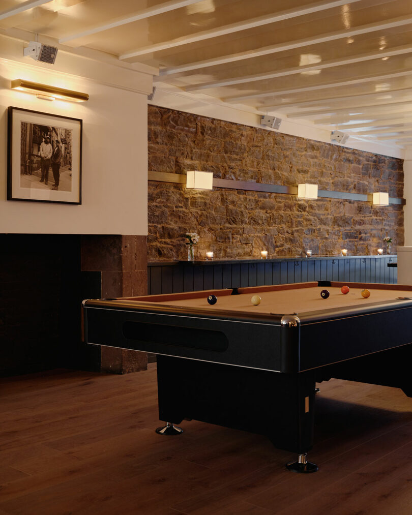 A signature camel-felt pool table in a room with historic stone walls and modern lighting at Jac's on Bond.