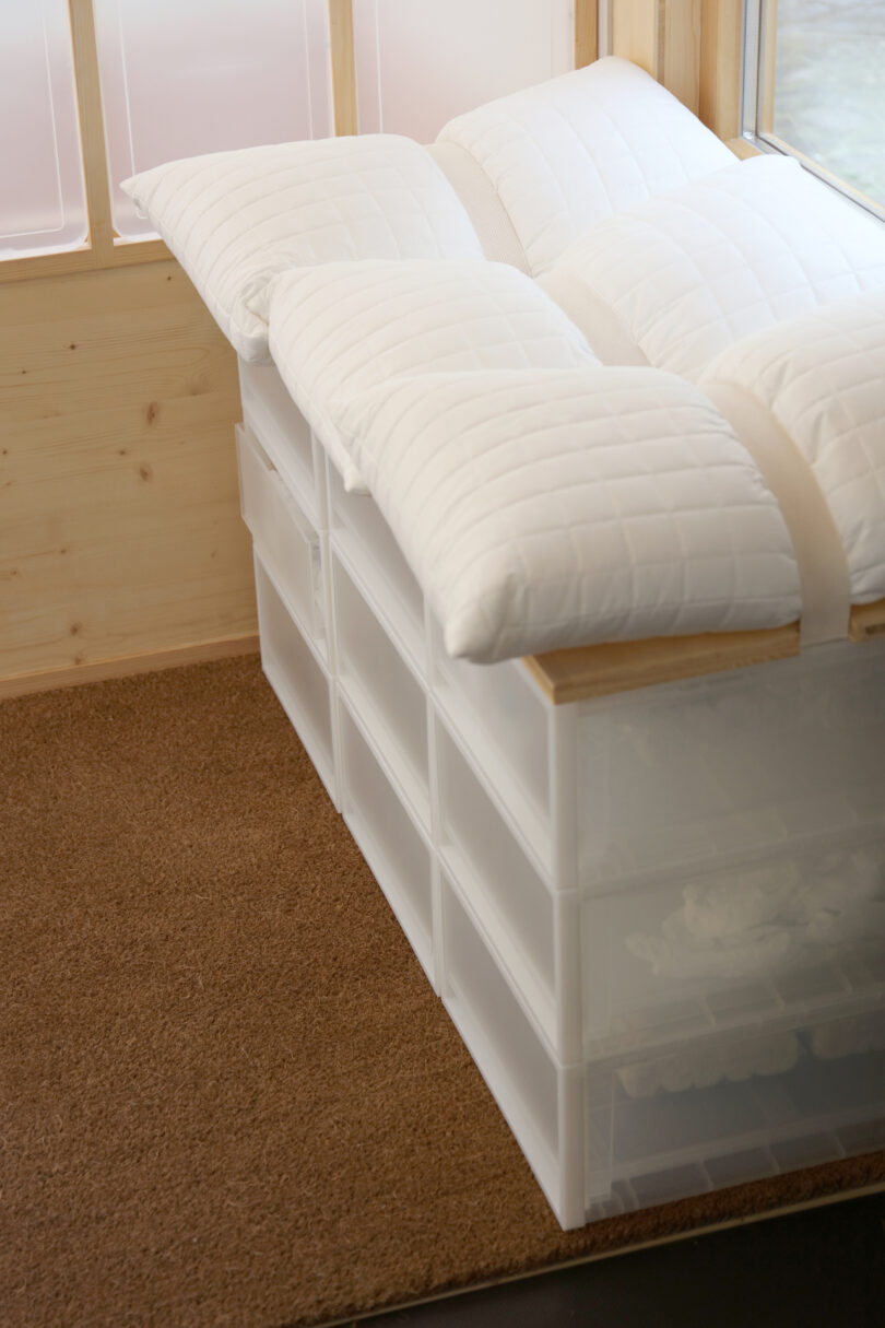 A low bench created by stacking white MUJI storage drawers with pillows on top.