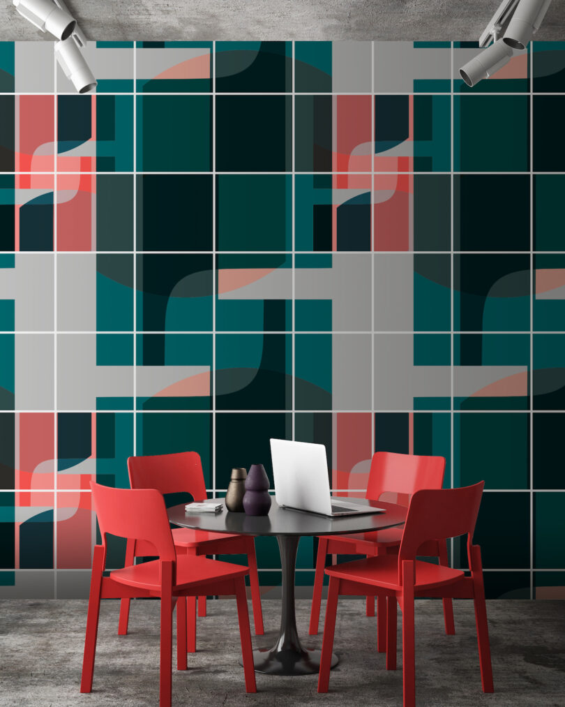 A modern room with a laptop on a round table set against a bold geometric-patterned wall.