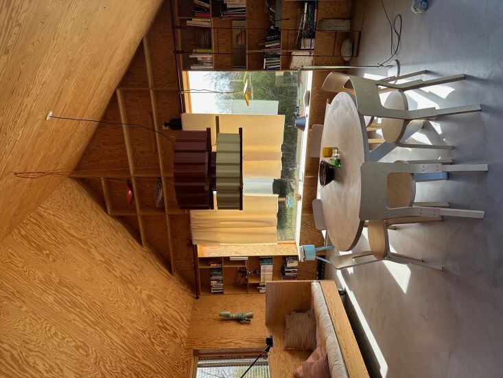 Dining area with Artek 66 chairs, a custom table, and long curtains framing the view.