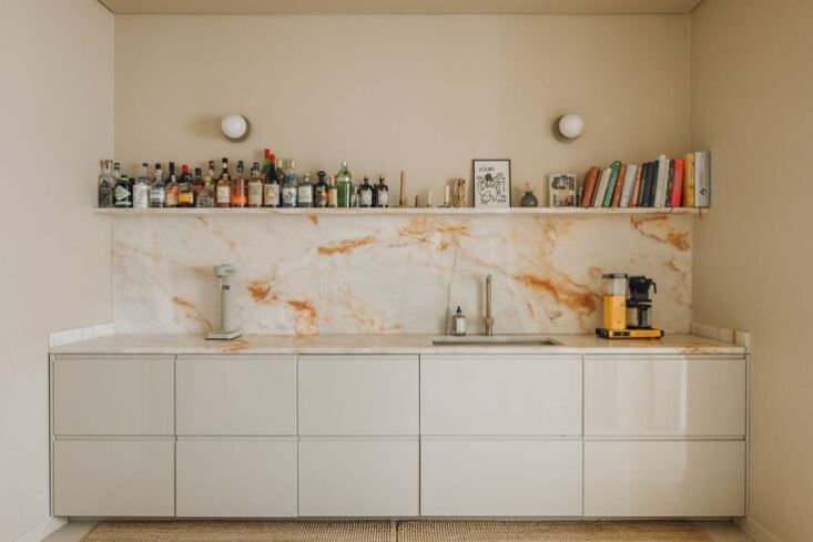 A modern kitchen in Lisbon with a prominent veined marble backsplash and high-end range.