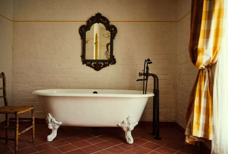 A bathroom featuring a vintage claw-foot bathtub and antique furniture.