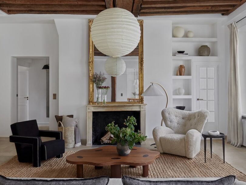 Stylish living room with modern seating, a spherical paper lantern, and a large mirror reflecting a refined interior.