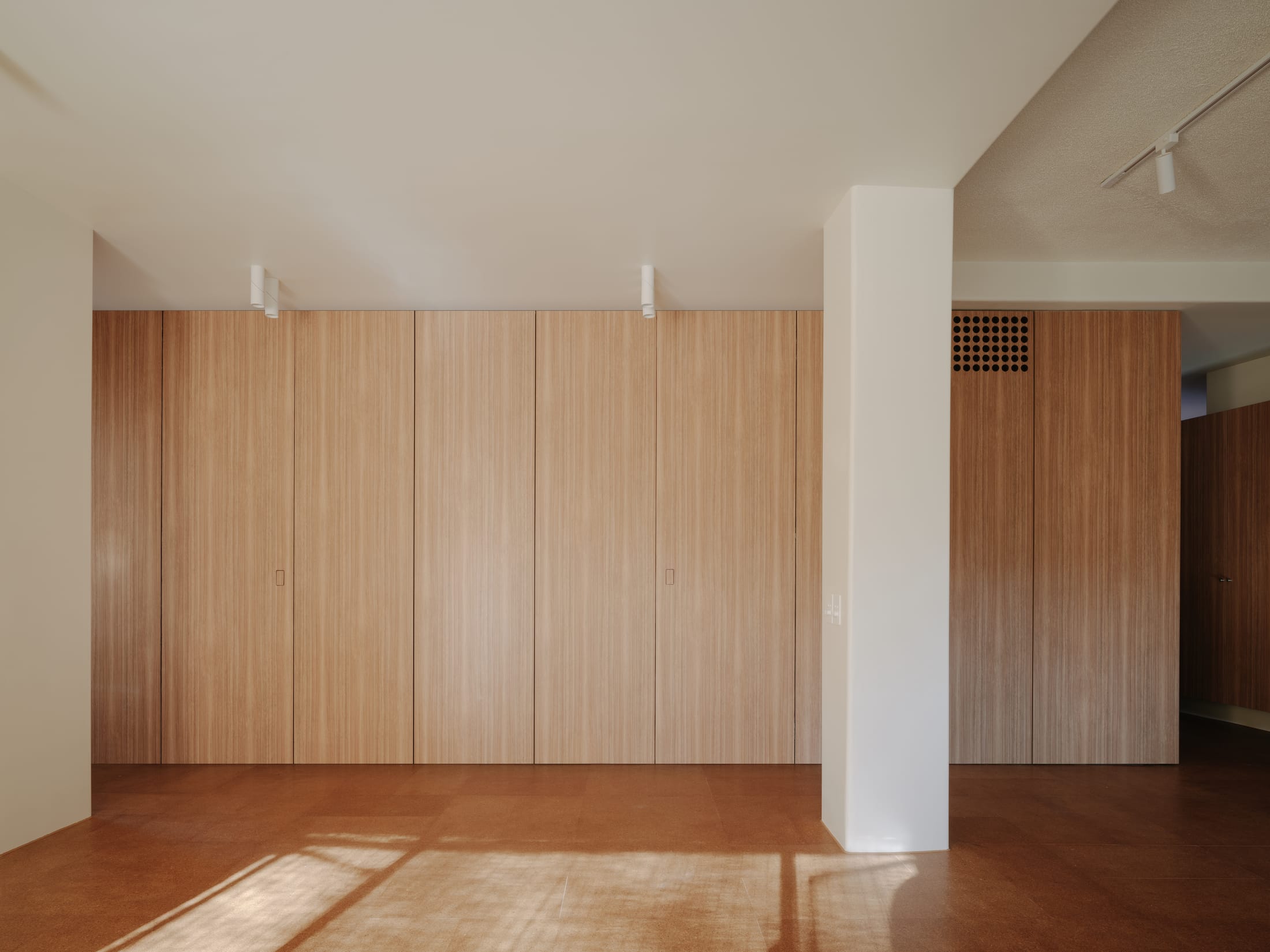 A minimalist workspace within the apartment featuring acoustic treatments and timber accents.
