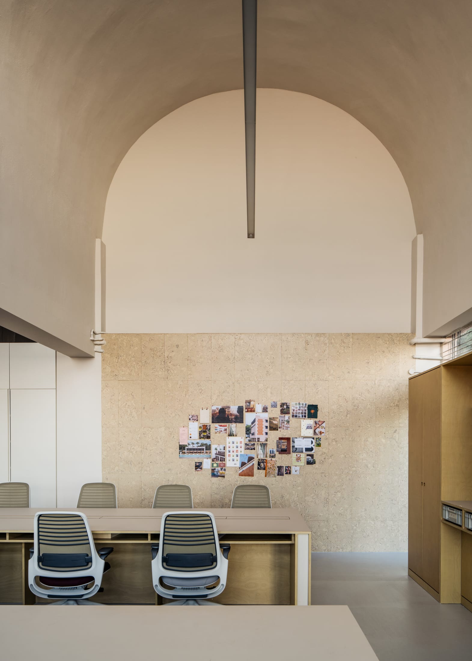 Detail of burnt red timber cabinetry and cork wall panels in the office interior.