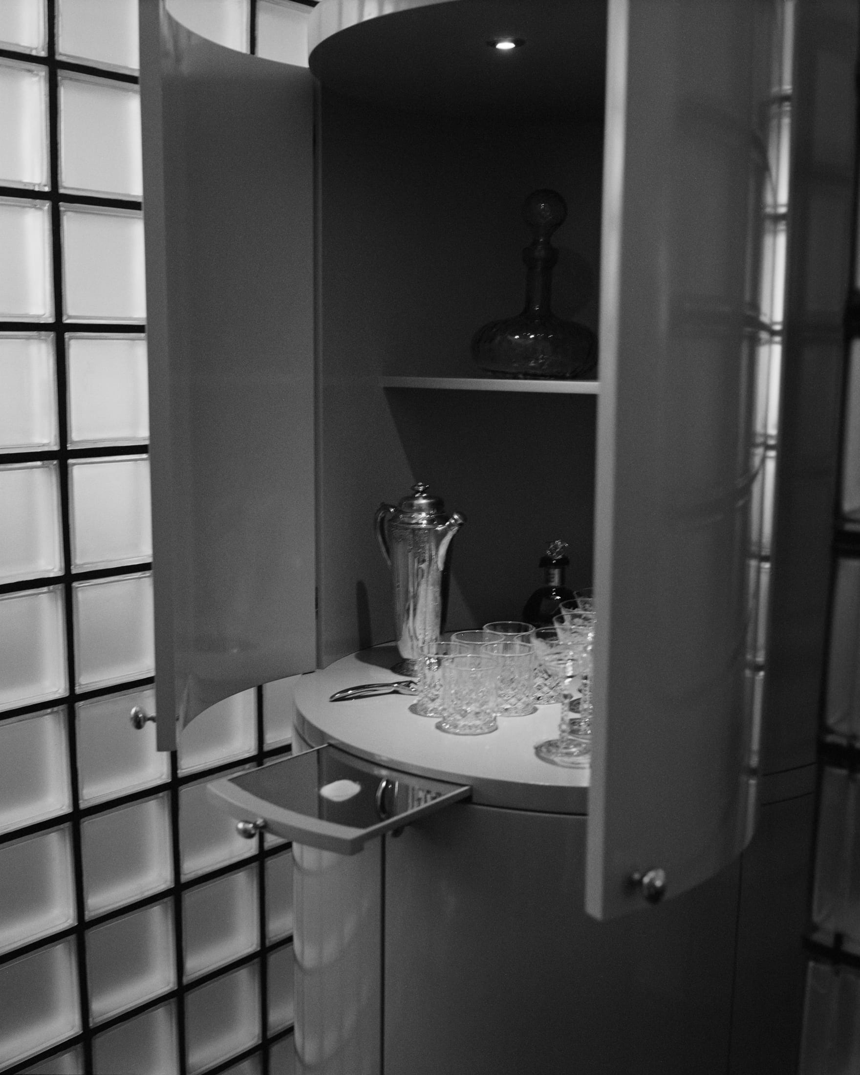 A minimalist shelf with curated objects and hidden tech integration in a professional studio setting.