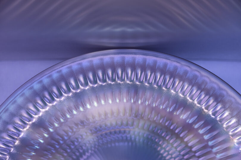 Macro shot of an iridescent blue and purple ridged ceramic surface.