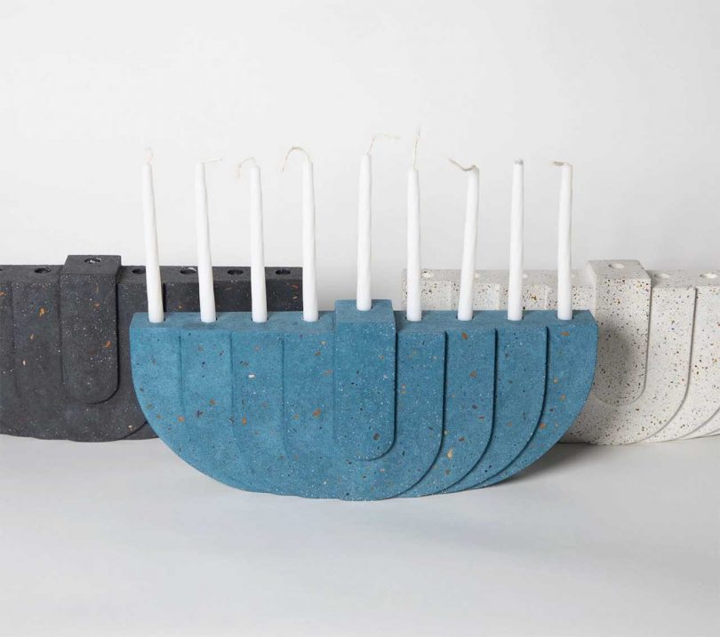 A set of three concrete terrazzo menorahs in different colors with speckled textures.