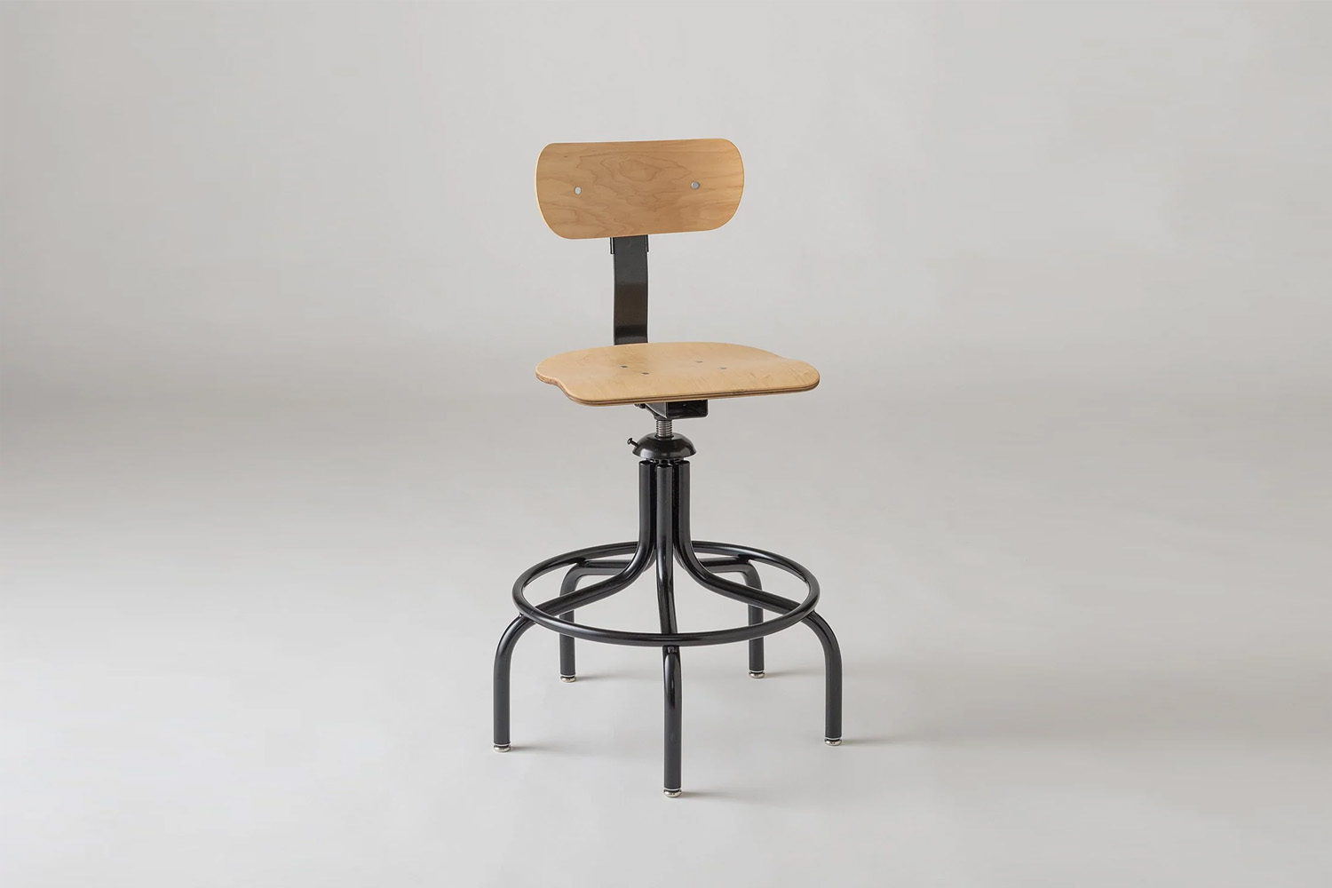 A vintage-inspired drafting stool made of wood and dark iron.