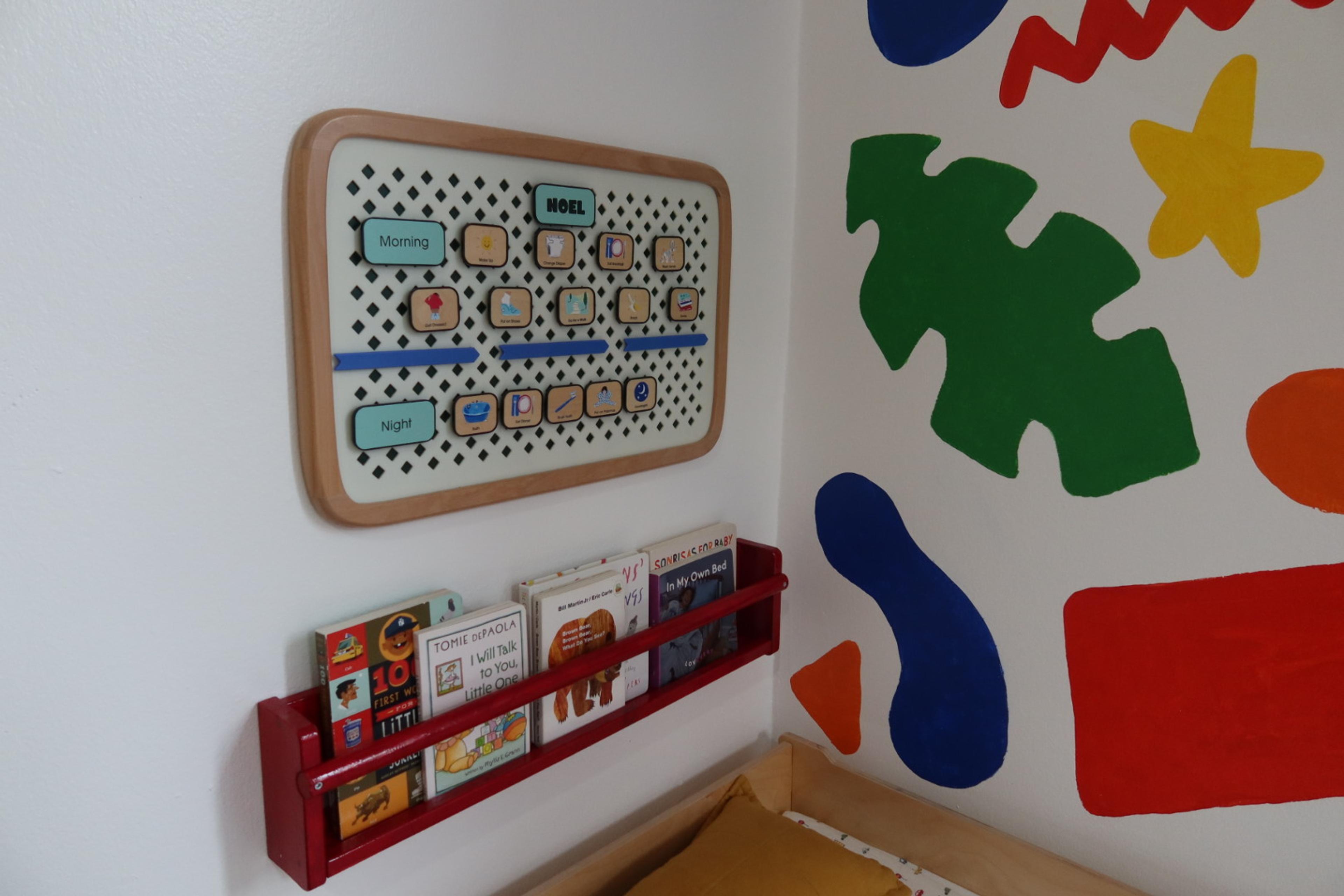 Close-up of a wall-mounted calendar and minimalist decor above a nursery dresser.