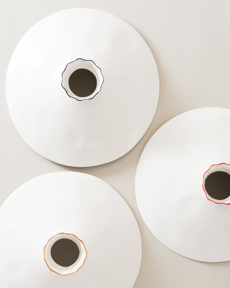 Top-down view of white ceramic vessels featuring hand-painted rims in blue, red, and gold.