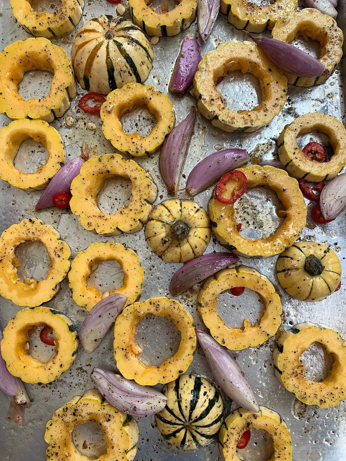 Whole and halved raw delicata squash showing their characteristic green stripes and yellow flesh.