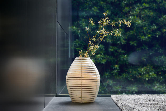 A large, sculptural paper lantern shaped like an oversized vase or table lamp, showcasing the texture of the washi paper.