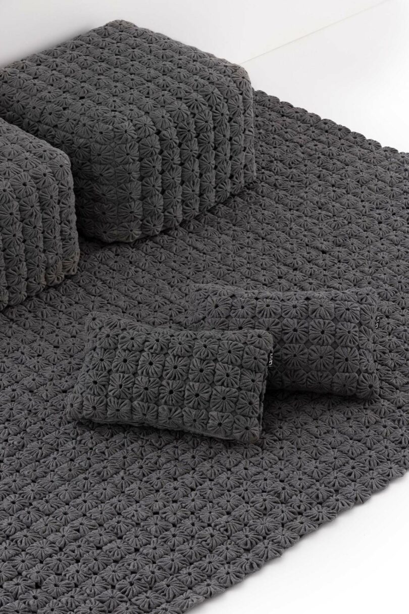 Close-up detail of gray textured cushions showing a flower-like geometric embroidery pattern.