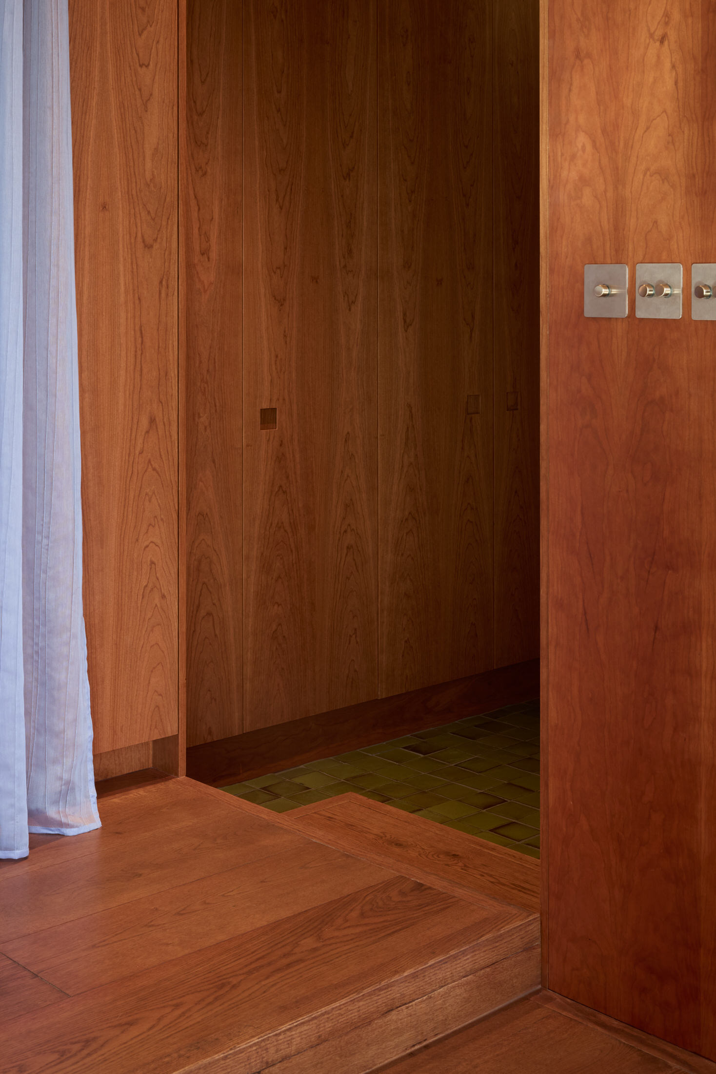 A corridor view leading to the bedroom with continuous wooden flooring.