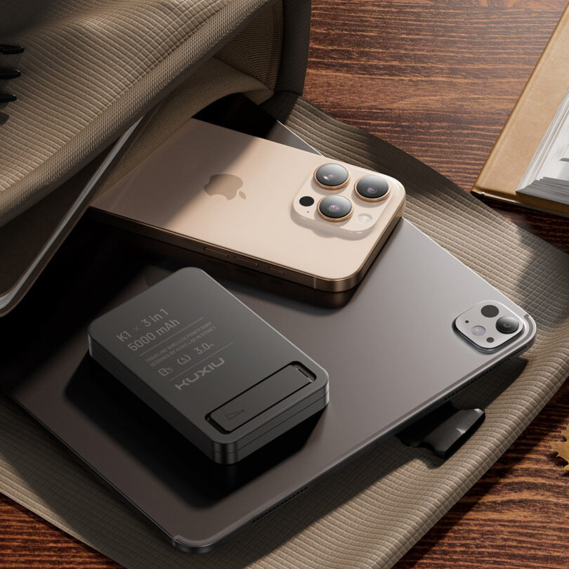 A Kuxiu portable charger, an iPhone, and an iPad tucked into a stylish travel bag.