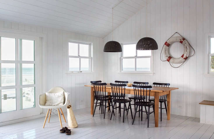 A vintage life preserver hung as art on a white shiplap wall.