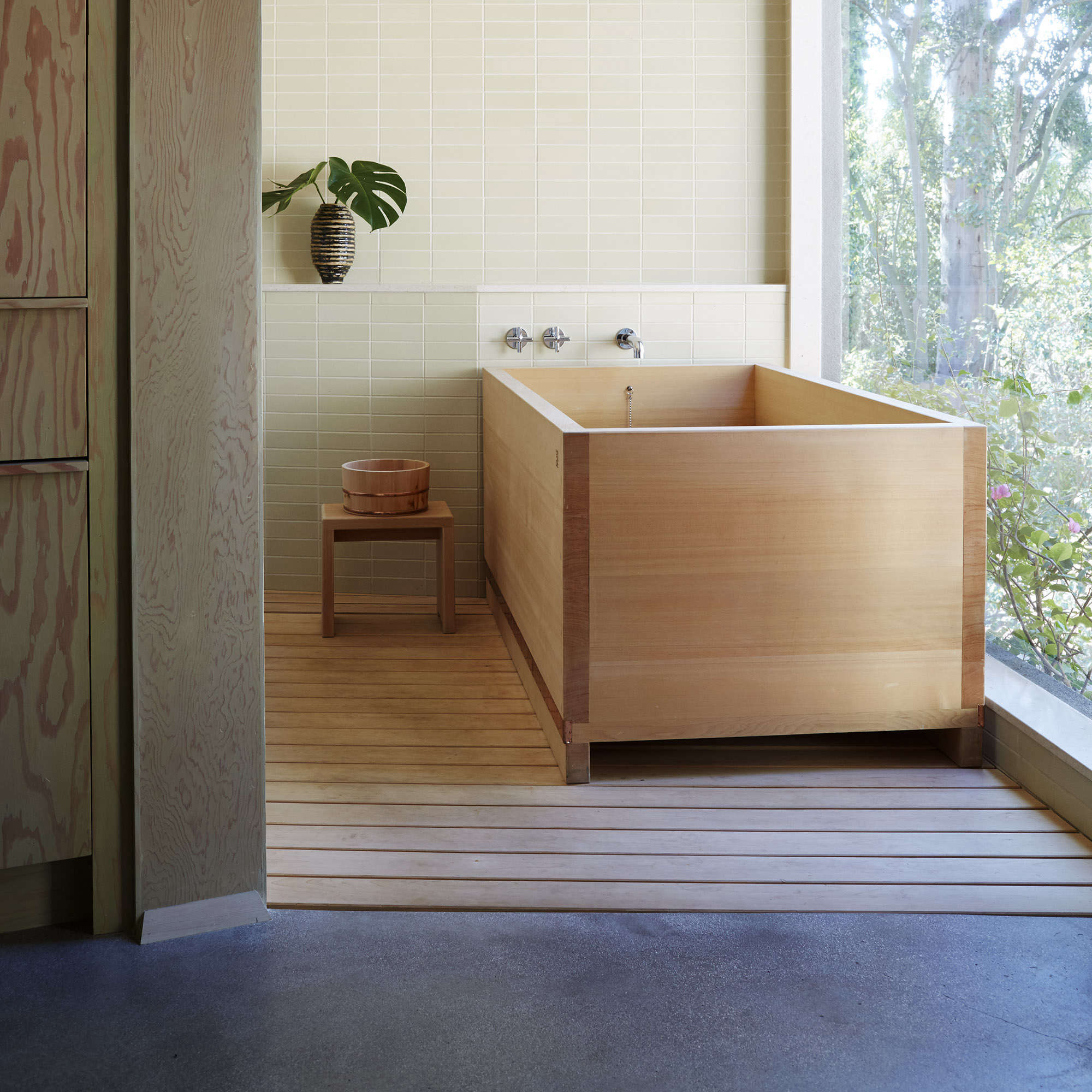 A bright, modern bathroom featuring a wooden tub and natural materials.