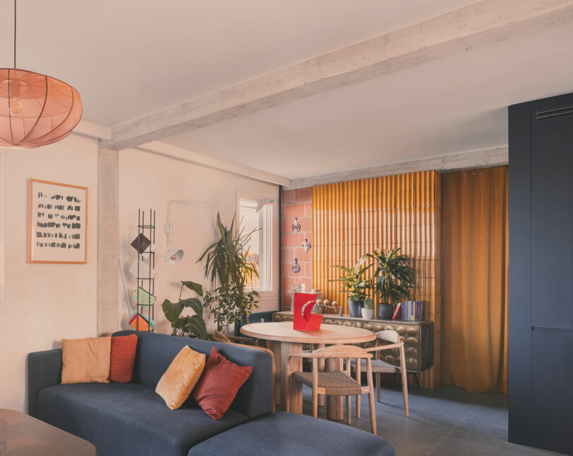 Living area featuring a blue sectional sofa and floor-to-ceiling golden-yellow velvet curtains.