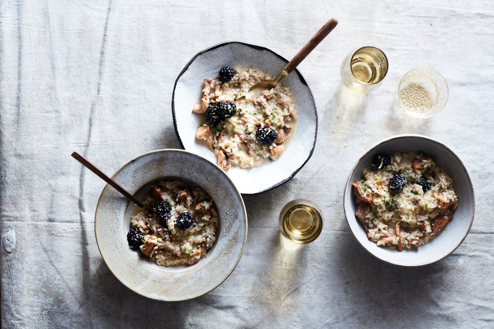 Close-up of creamy risotto with visible wild mushrooms and fresh herb garnishes.