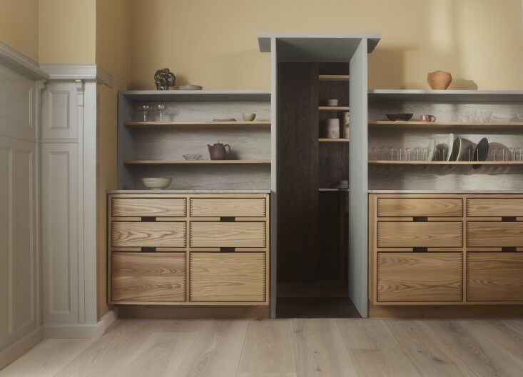 A straight view into a wood-framed larder showing the contrast between blueish Ash Oil wood and dark painted paneling.