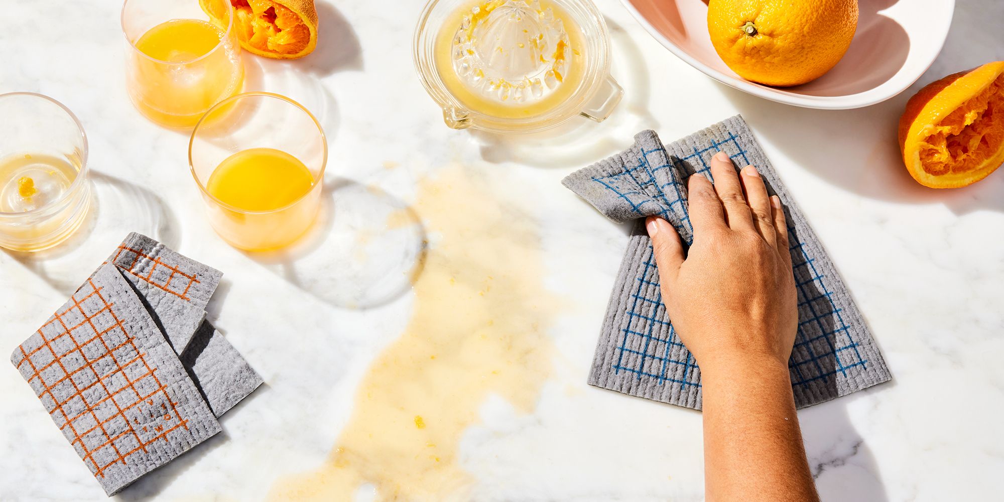A person using a cloth and citrus to clean a white marble countertop.