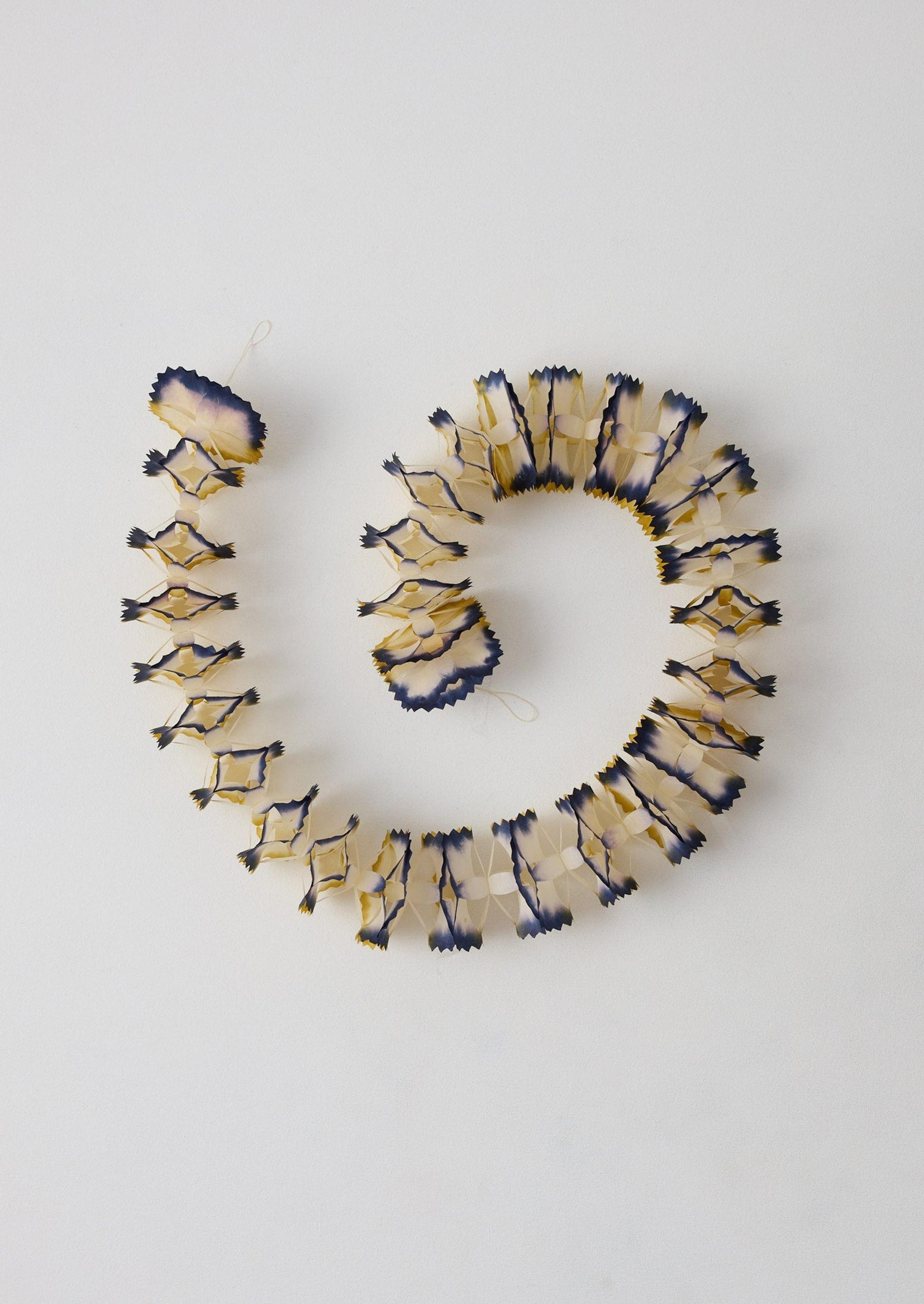 Artistic dip-dyed paper streamers in deep blue and green tones draped as holiday garlands.