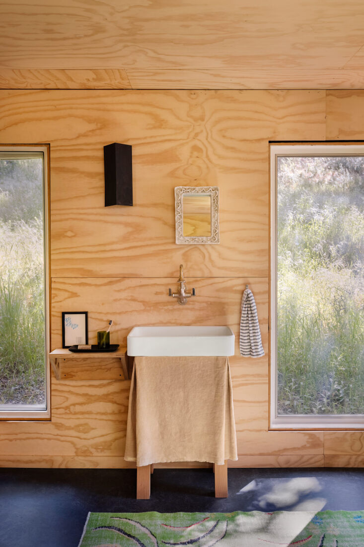 A neutral-toned fabric sink skirt in a modern, minimalist bathroom designed by Charles de Lisle.