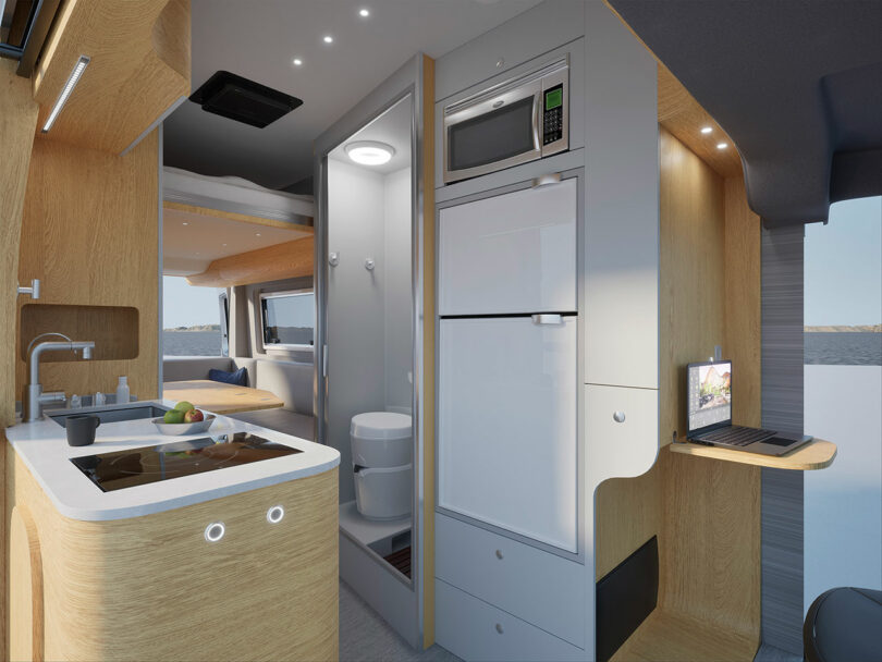 A wide shot of the van's interior showing the kitchen sink, built-in bathroom, and modern white appliances.