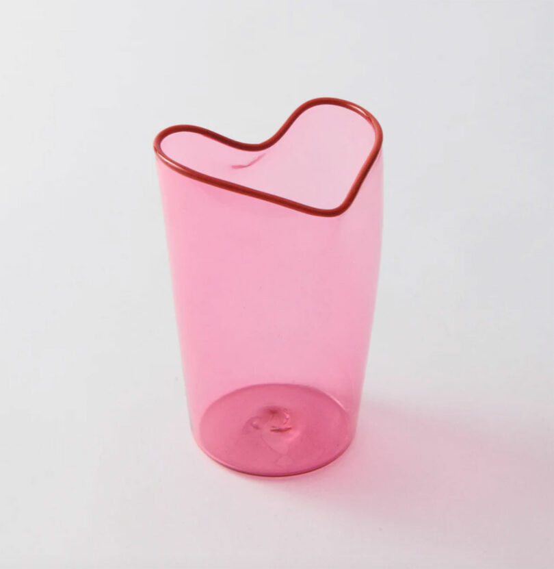 A translucent pink handblown glass cup with a distinctive heart-shaped rim.