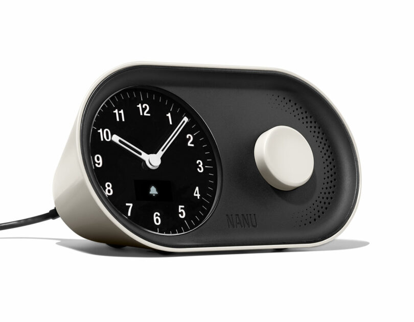 Modern black analog alarm clock with a circular dial and a small digital bell icon on the face.