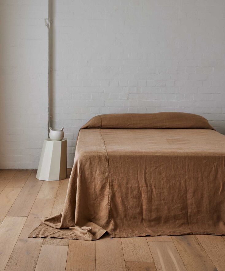 A Sand-colored Heavyweight Linen Bedcover from Cultiver styled on a large bed.
