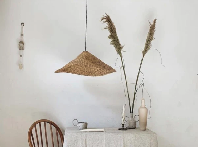Minimalist dining room featuring a woven pendant light, pampas grass, and neutral tones.