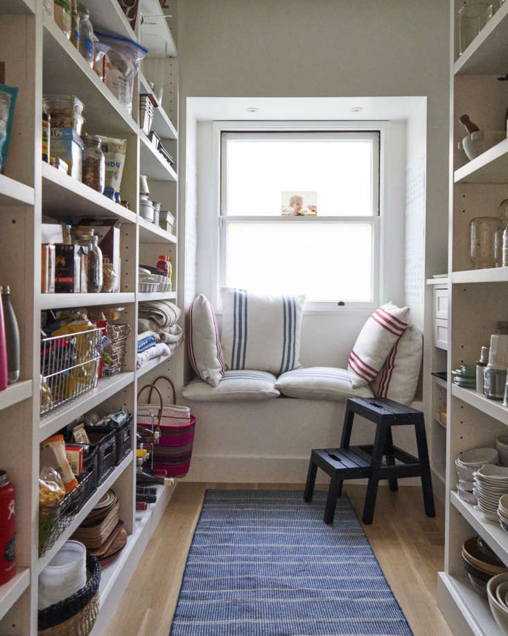 A cozy pantry area with northern light, a runner rug, and seating used for writing and escaping the main kitchen activity.