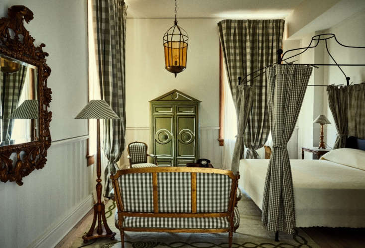 A hotel guest room with oversized sash windows and a hand-painted wardrobe.