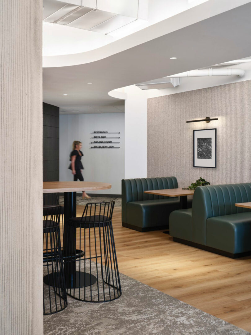 Modern office lounge with teal leather booth seating, industrial lighting, and wooden floors.