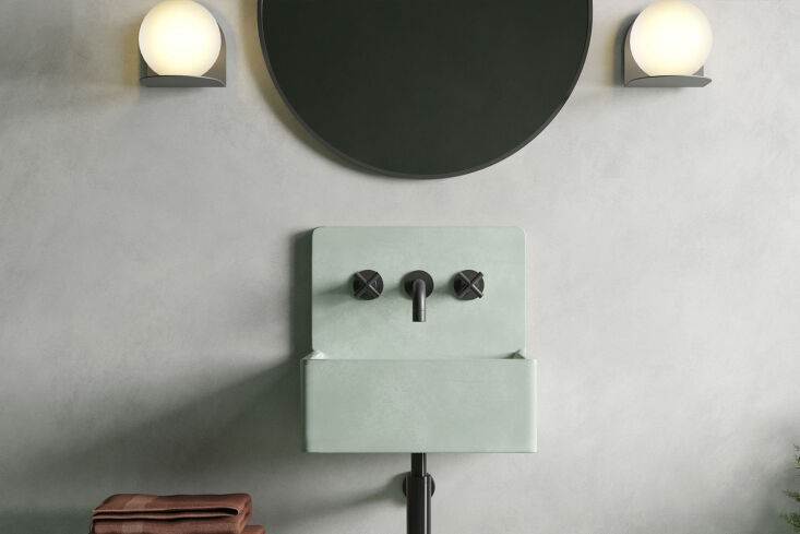 A small, sculptural pedestal sink in a terracotta 'San Terra' color.