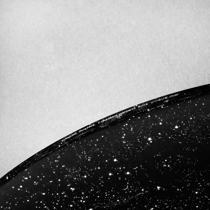 A macro shot of a black glass surface with white specks resembling a star-filled galaxy.