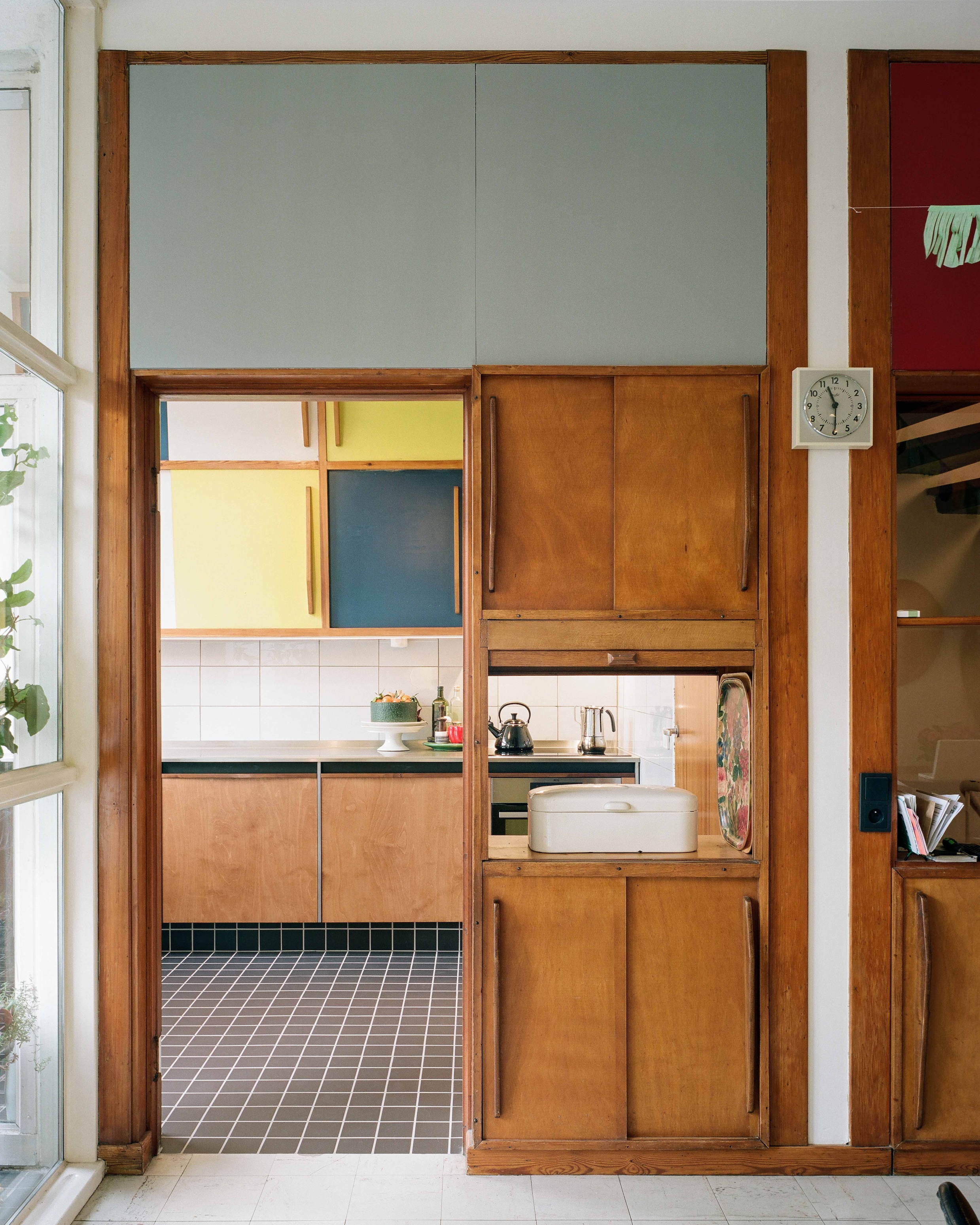 Canted upper kitchen cabinets painted in original primary colors of yellow, blue, and white.