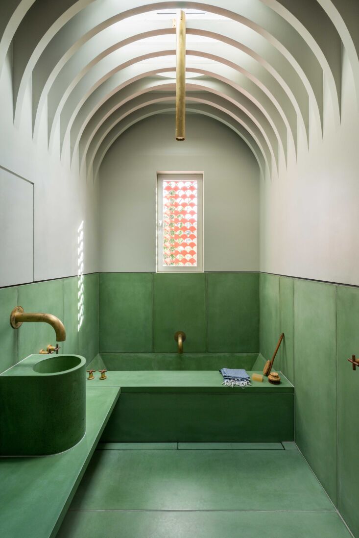 A hamman-style wet room featuring green-pigmented concrete walls and floor.