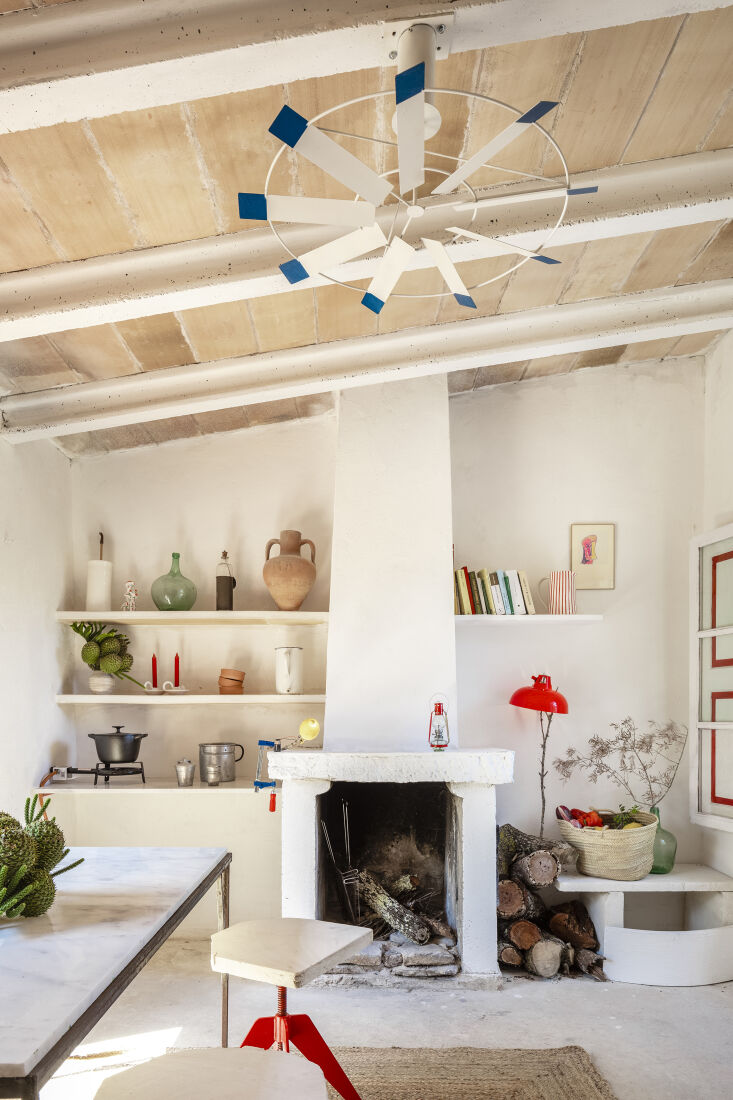Interior view of the original fireplace alongside simple shelving and a solar-powered ceiling fan.