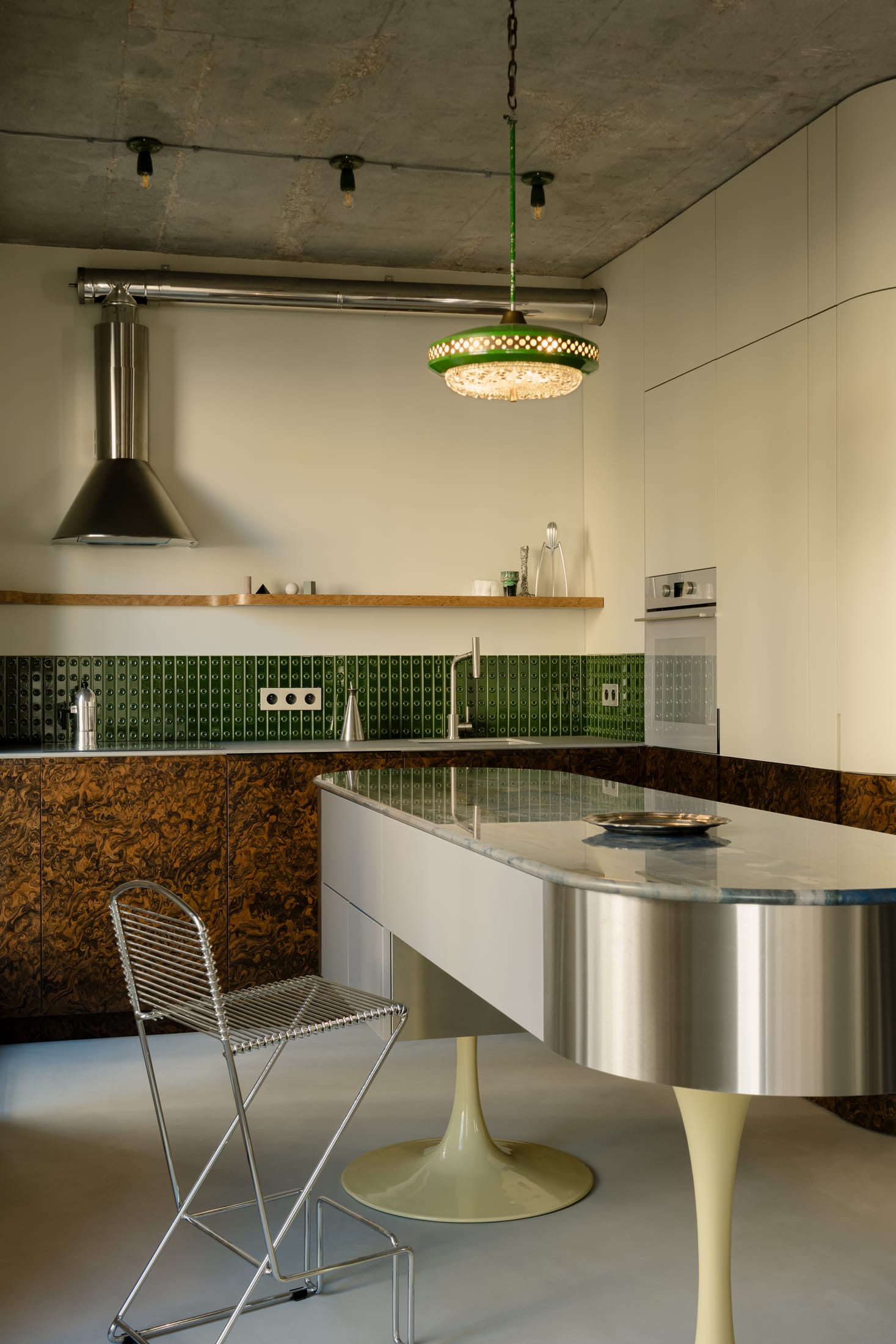 Stainless steel oval kitchen island with blue quartzite top and bright yellow legs.