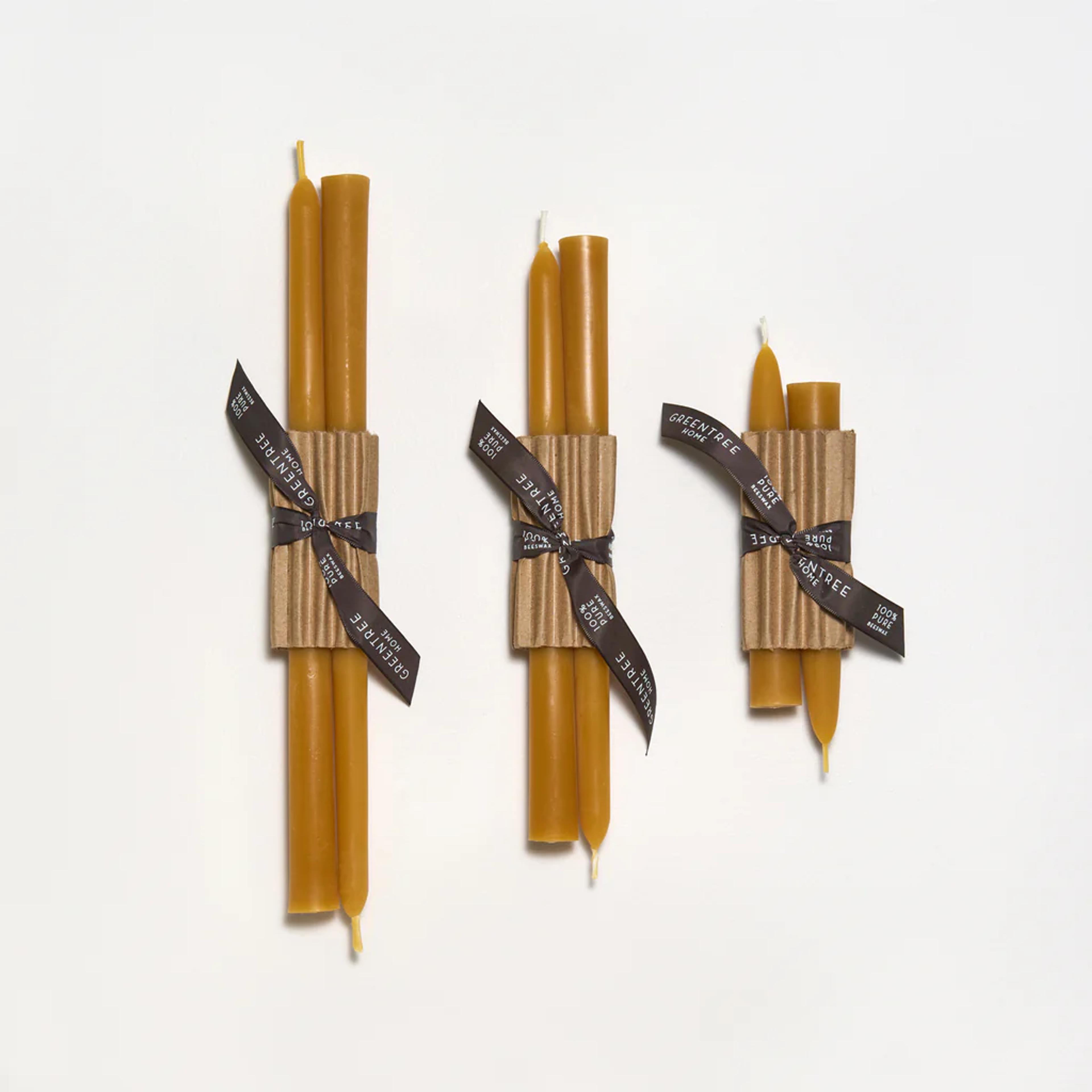 A pair of natural beeswax taper candles in a minimalist holder.
