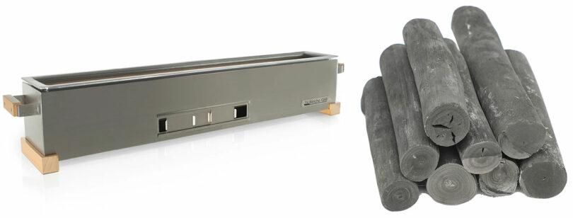 A long rectangular charcoal grill and a stack of cylindrical Binchotan charcoal logs.