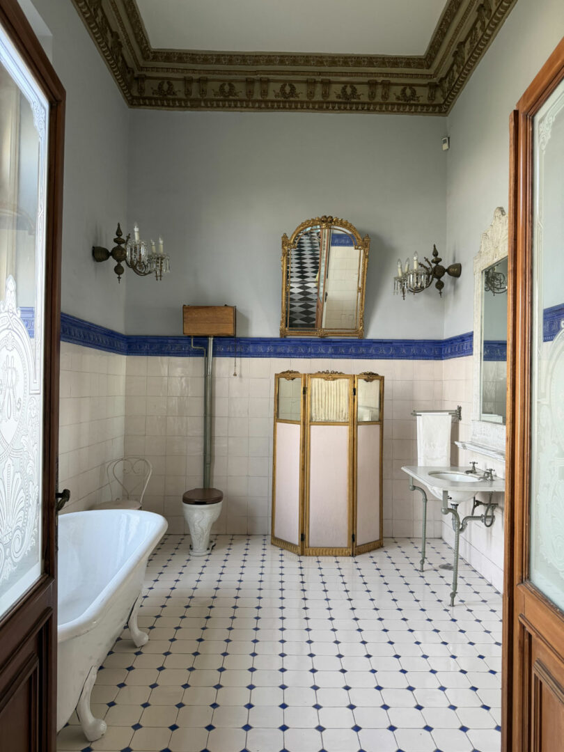 Vintage bathroom with a clawfoot tub, ornate wooden toilet, and a large decorative mirror.