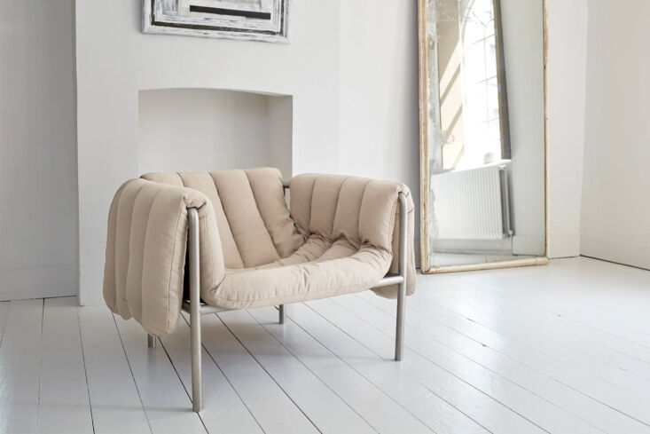 The Hem Puffy Lounge Chair by Faye Toogood, featuring a thick, draped natural-colored cushion over a minimalist metal frame.