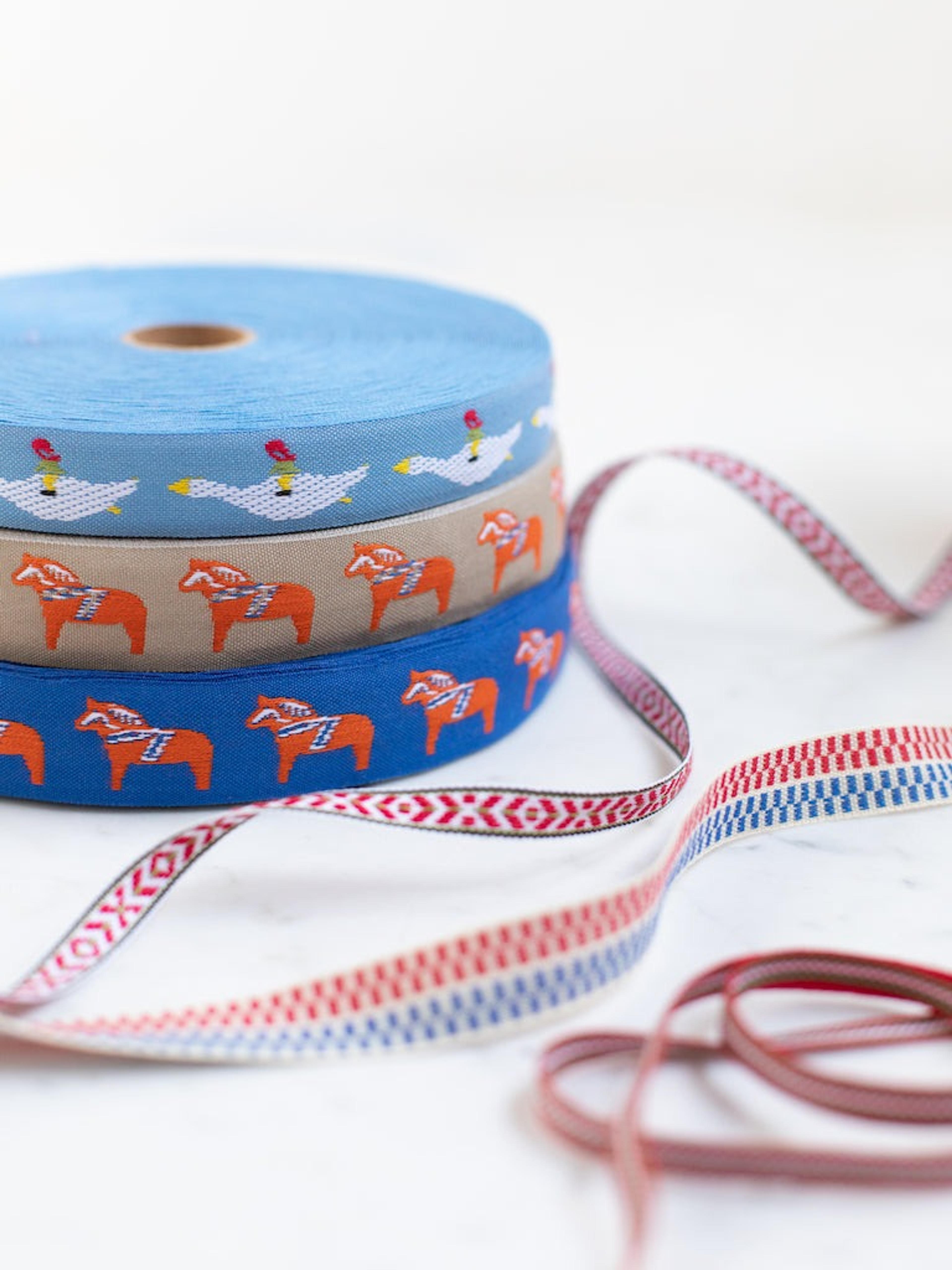 Several rolls of patterned Swedish fabric ribbons in traditional red and white designs.